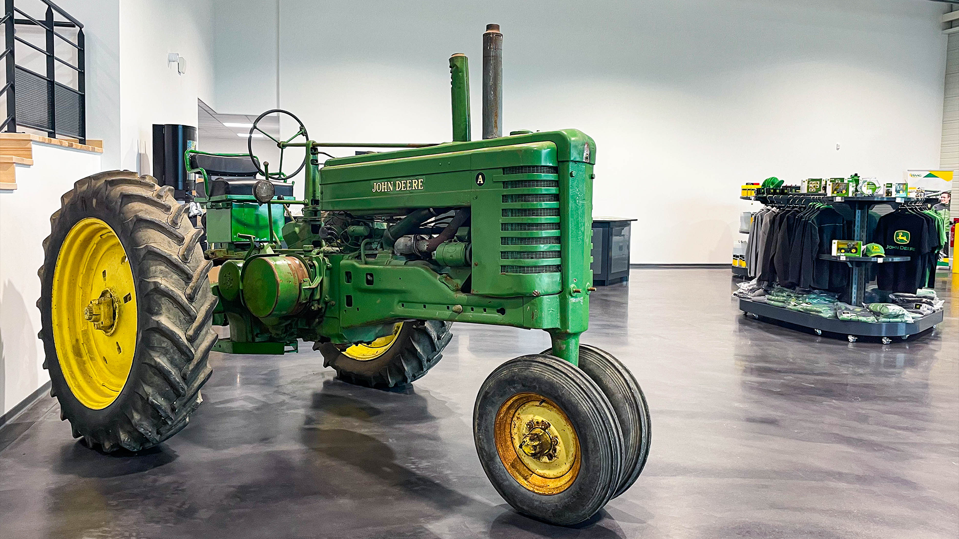 Tracteur John Deere de collection vert et jaune exposé dans le showroom de la nouvelle base HAAG de Lérouville avec boutique en arrière-plan