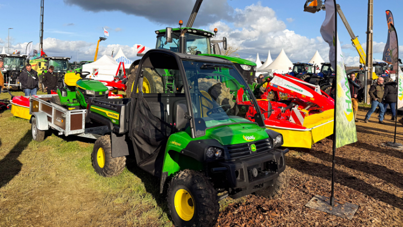 Véhicule utilitaire John Deere Gator vert exposé avec tracteurs et matériel agricole rouge sur le stand HAAG à la Foire de Poussay